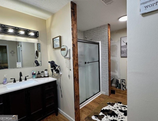 bathroom with vanity, a textured ceiling, hardwood / wood-style flooring, and a shower with door