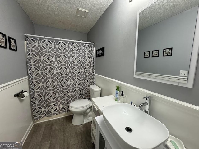 bathroom with sink, walk in shower, wood-type flooring, a textured ceiling, and toilet