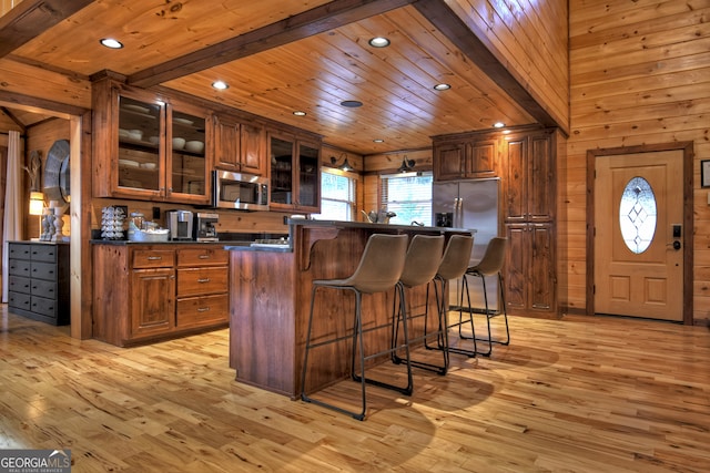 kitchen featuring beam ceiling, appliances with stainless steel finishes, wood ceiling, and light hardwood / wood-style flooring