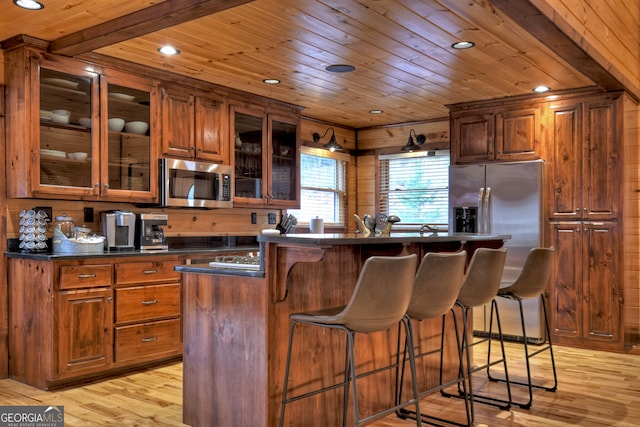 kitchen featuring stainless steel appliances, light hardwood / wood-style floors, and wood ceiling