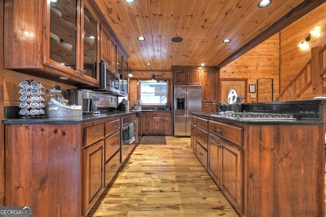 kitchen featuring stainless steel appliances, wooden walls, light hardwood / wood-style floors, and wooden ceiling