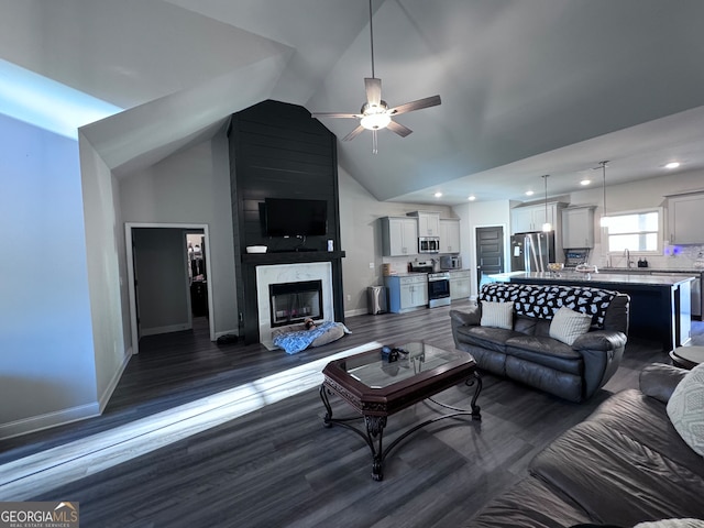 living room with ceiling fan, a premium fireplace, high vaulted ceiling, dark wood-type flooring, and sink