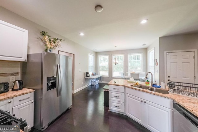 kitchen featuring hanging light fixtures, sink, dark wood-type flooring, white cabinetry, and stainless steel appliances