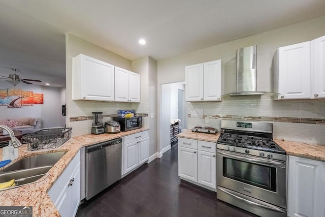 kitchen with sink, wall chimney exhaust hood, white cabinetry, stainless steel appliances, and dark hardwood / wood-style flooring