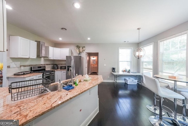 kitchen featuring appliances with stainless steel finishes, wall chimney exhaust hood, a wealth of natural light, and hanging light fixtures