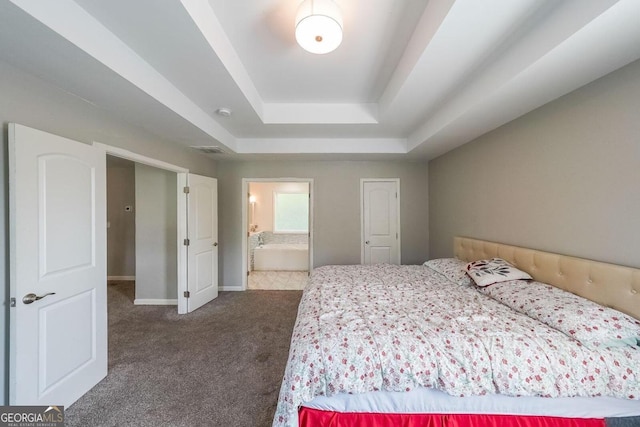 carpeted bedroom featuring a raised ceiling and ensuite bath