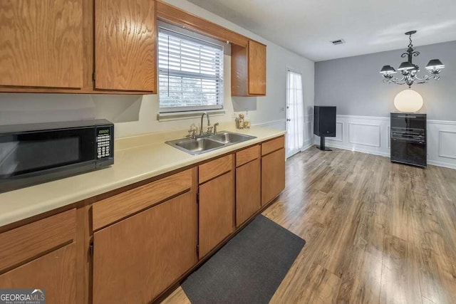 kitchen featuring a notable chandelier, hanging light fixtures, sink, and light hardwood / wood-style flooring