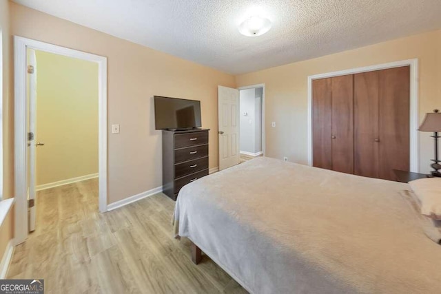 bedroom with a textured ceiling, a closet, and light hardwood / wood-style floors