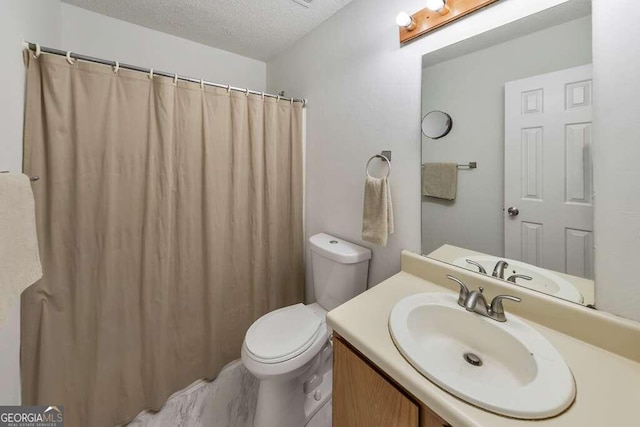 bathroom with a textured ceiling, vanity, and toilet