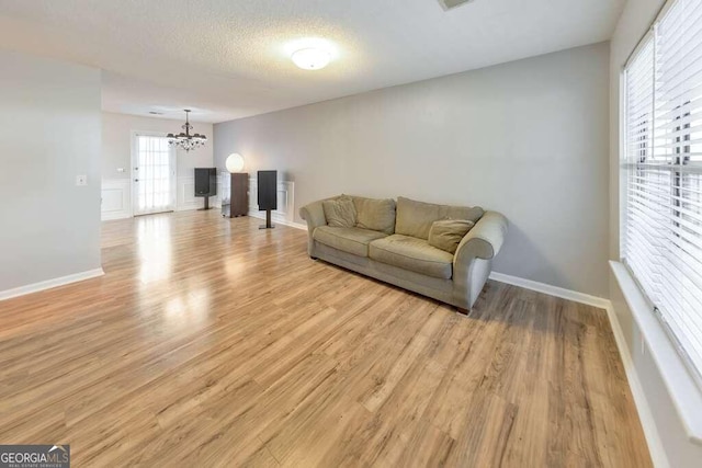 living room featuring a notable chandelier, light hardwood / wood-style flooring, and a textured ceiling