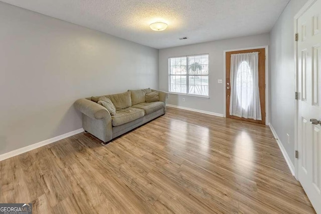 unfurnished living room with a textured ceiling and light hardwood / wood-style flooring