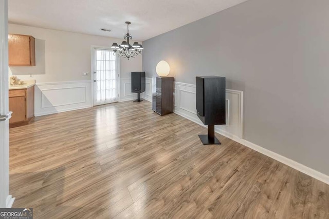 unfurnished living room featuring a notable chandelier and light hardwood / wood-style floors