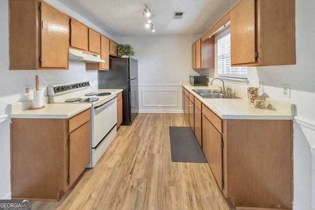 kitchen with electric range, black fridge, sink, and light wood-type flooring