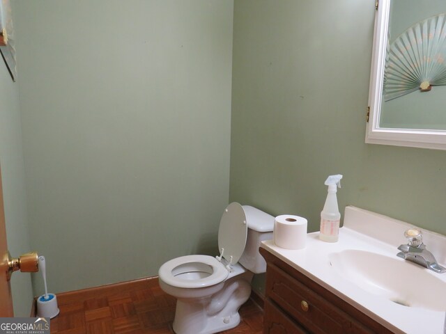 bathroom with vanity, parquet flooring, and toilet