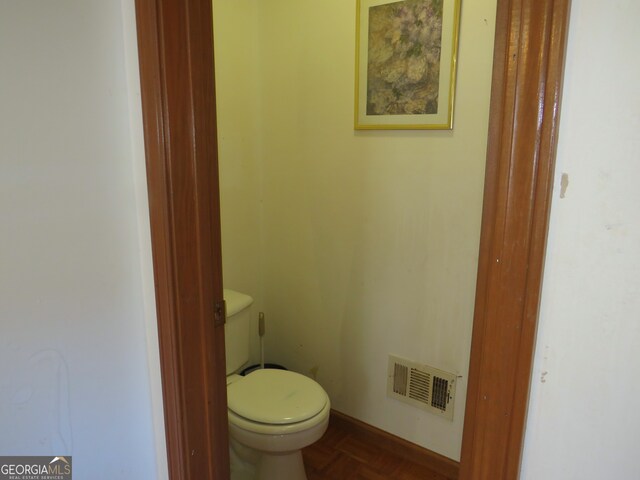 bathroom featuring parquet flooring and toilet