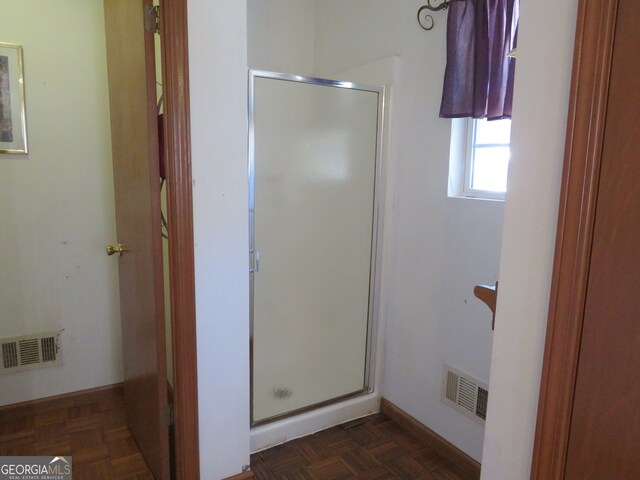 bathroom with an enclosed shower and parquet flooring