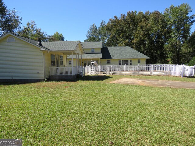 rear view of house with a porch and a yard