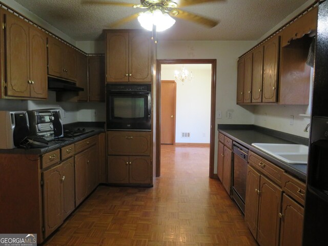 kitchen featuring black appliances, sink, ceiling fan with notable chandelier, dark parquet flooring, and a textured ceiling