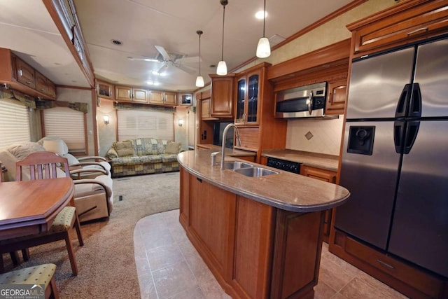 kitchen with an island with sink, decorative backsplash, sink, hanging light fixtures, and appliances with stainless steel finishes