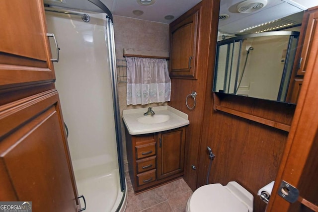 bathroom featuring tile patterned floors, toilet, vanity, and a shower with shower door