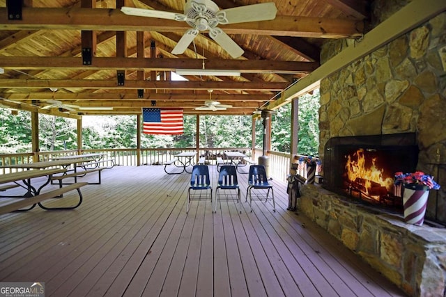 deck with ceiling fan and an outdoor stone fireplace