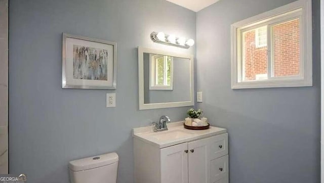 bathroom featuring vanity, a wealth of natural light, and toilet