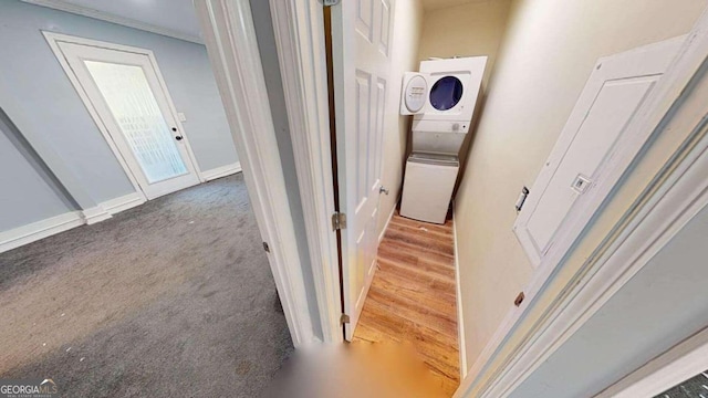 hall featuring ornamental molding, stacked washing maching and dryer, and hardwood / wood-style flooring