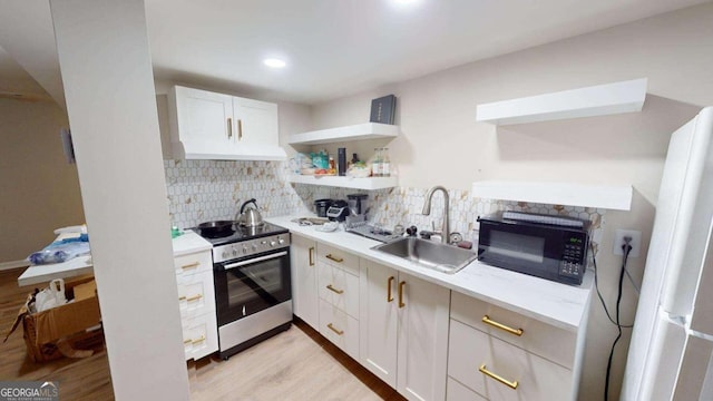 kitchen featuring light wood-type flooring, white cabinets, sink, and stainless steel stove