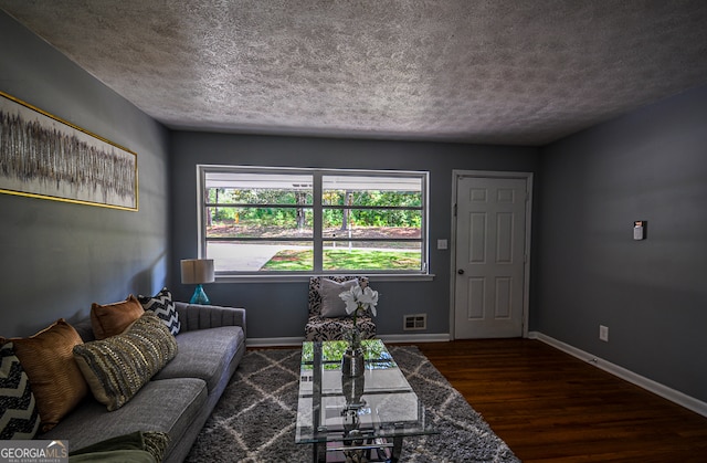 living room featuring dark wood-type flooring and a textured ceiling