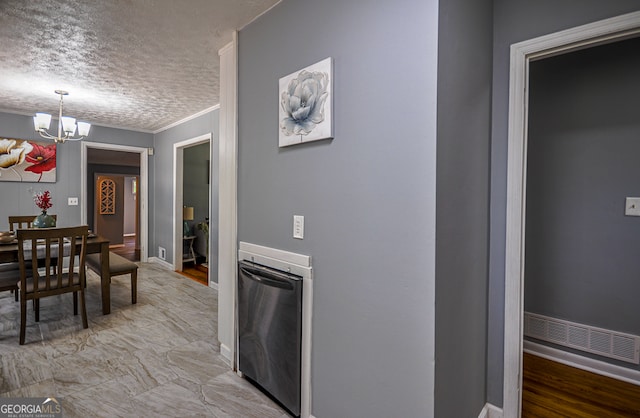 interior space featuring a notable chandelier, hanging light fixtures, light hardwood / wood-style flooring, ornamental molding, and a textured ceiling