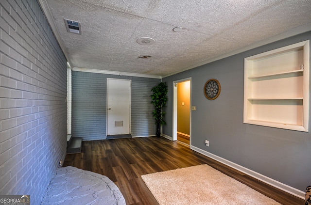 unfurnished bedroom featuring crown molding, dark hardwood / wood-style flooring, brick wall, and a textured ceiling