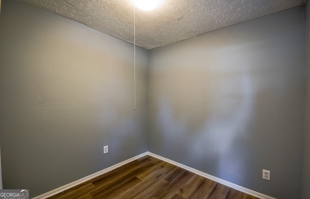 unfurnished room with hardwood / wood-style floors and a textured ceiling