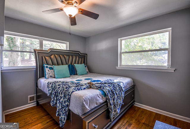 bedroom with ceiling fan, dark hardwood / wood-style floors, and multiple windows