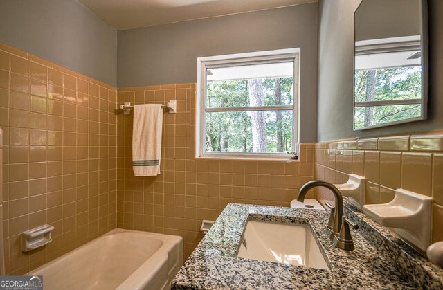 bathroom featuring tile walls, a tub to relax in, vanity, and toilet