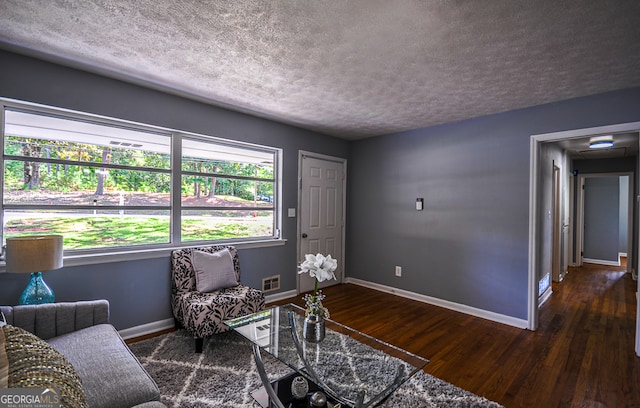 living area with dark wood-type flooring and a textured ceiling