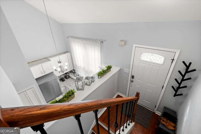 foyer entrance with lofted ceiling, an inviting chandelier, and dark hardwood / wood-style flooring