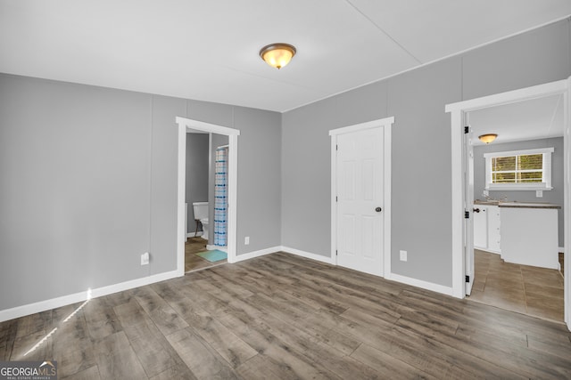 unfurnished bedroom featuring wood-type flooring and ensuite bath