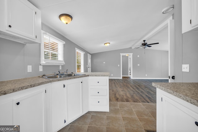 kitchen with hardwood / wood-style flooring, vaulted ceiling with beams, white cabinetry, and sink