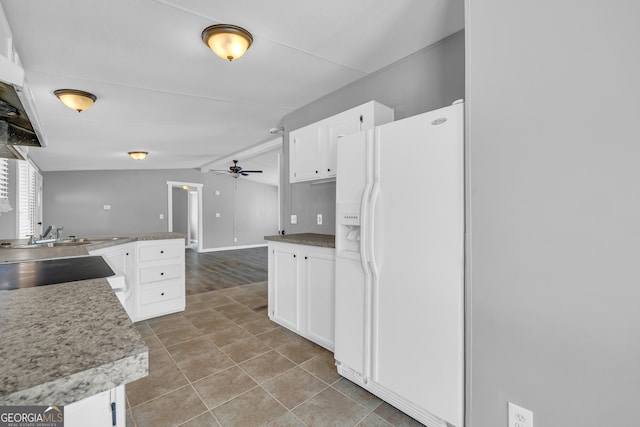 kitchen with ceiling fan, white refrigerator with ice dispenser, vaulted ceiling, and white cabinets