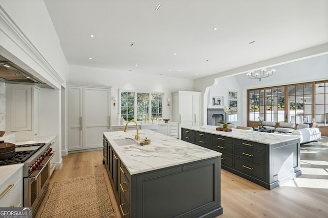 kitchen featuring sink, range with two ovens, plenty of natural light, and an island with sink