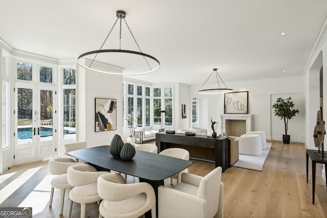 dining room with a wealth of natural light, crown molding, light hardwood / wood-style floors, and french doors