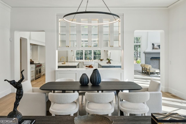 dining space with a chandelier, crown molding, a healthy amount of sunlight, and light wood-type flooring