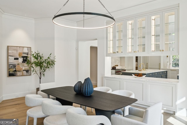 dining area with light hardwood / wood-style floors, ornamental molding, and sink