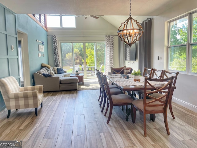 dining area featuring light hardwood / wood-style floors, ceiling fan with notable chandelier, and vaulted ceiling