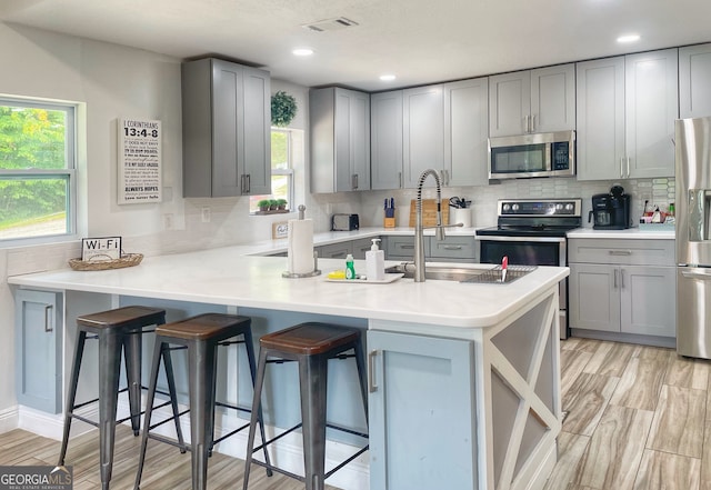 kitchen with appliances with stainless steel finishes, kitchen peninsula, and a healthy amount of sunlight