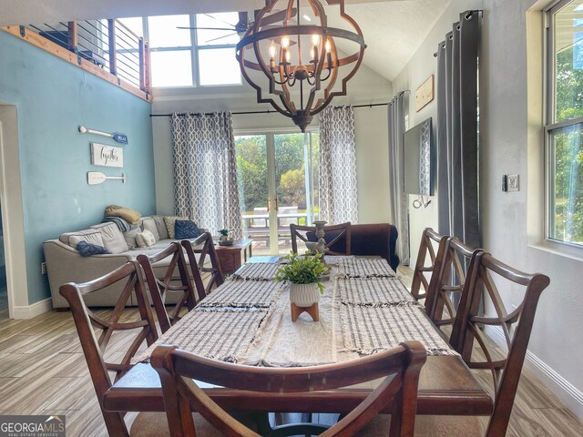 dining room featuring lofted ceiling, a chandelier, and light hardwood / wood-style floors