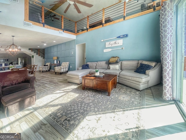 living room with a high ceiling and ceiling fan with notable chandelier