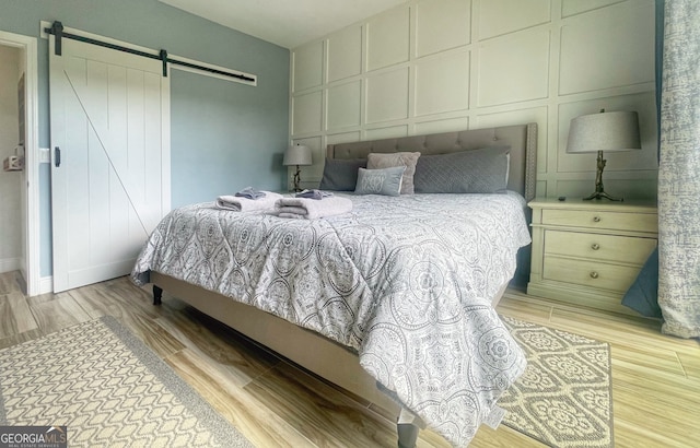 bedroom featuring a barn door and light wood-type flooring