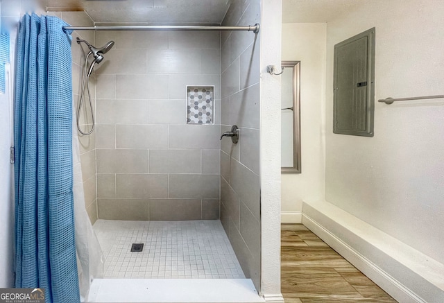 bathroom with electric panel, a shower with shower curtain, and hardwood / wood-style floors