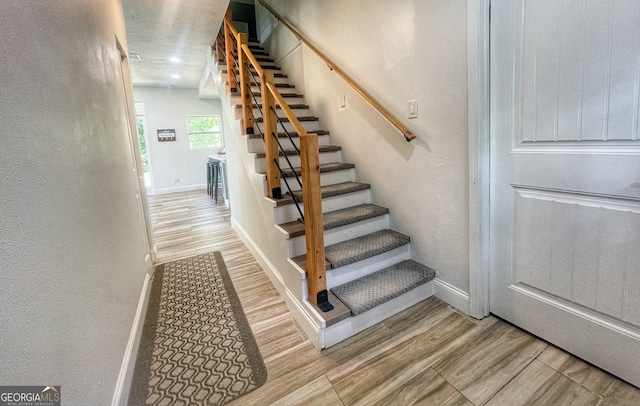 stairs featuring hardwood / wood-style floors and a textured ceiling